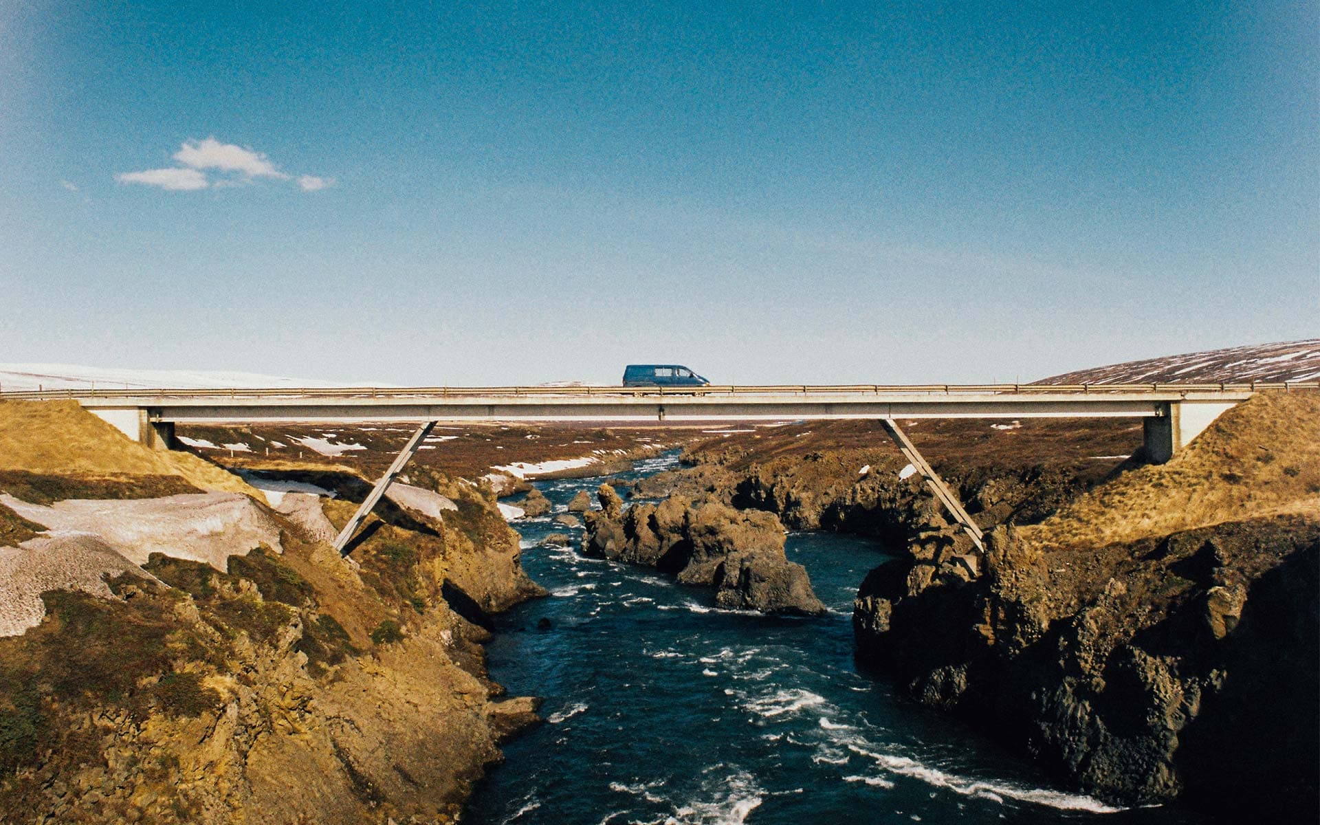 Van aménagé traversant un pont au-dessus de la mer